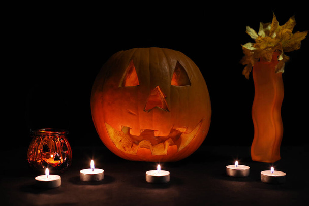 Orange pumpkin for Halloween on a black background with candles. Halloween concept. - 写真・画像