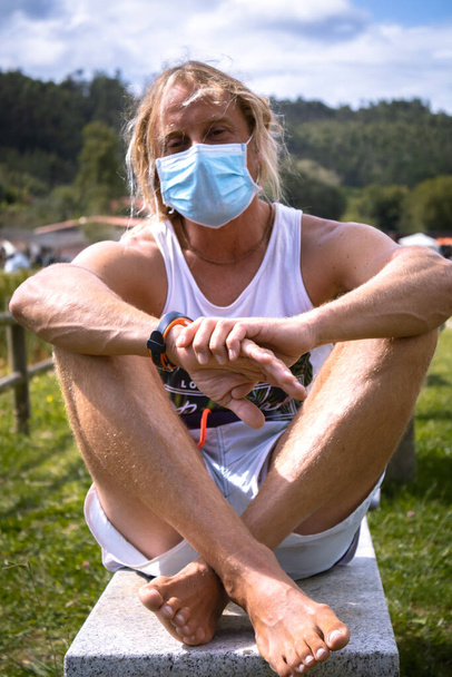Mann mit OP-Verband im Freien, medizinische Maske, Porträt eines Mannes mit See im Hintergrund - Foto, Bild