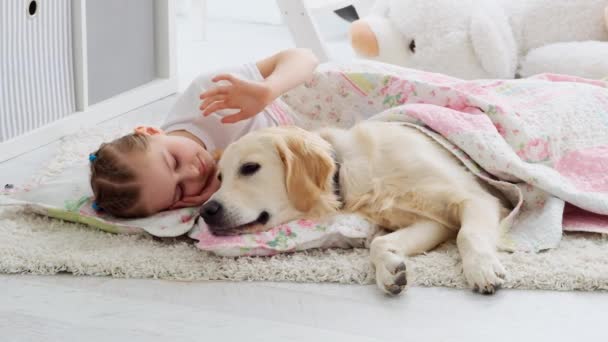Cute little girl caressing dog under blanket - Video