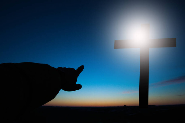 Крест Иисуса на фоне неба и облаков. Свет падает на крест. Точки - Фото, изображение