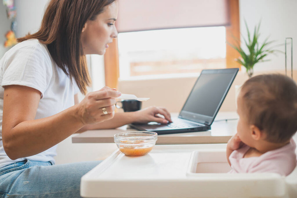 Mãe alimentar sua filhinha com uma colher e procurar na internet receitas de alimentos - Foto, Imagem