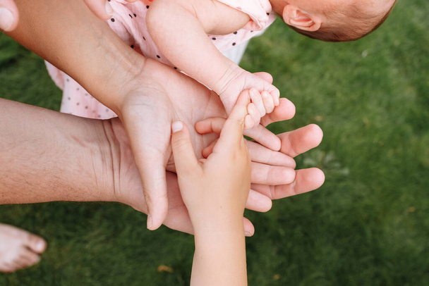 Handen van de hele familie. Handen van mama, papa en kinderen. Vier handen van de familie. Het concept van eenheid, steun, bescherming en geluk - Foto, afbeelding
