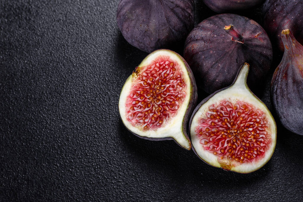 Świeże dojrzałe figi na ciemnym stole. Zdrowe śródziemnomorskie owoce figowe. Świeże figi na czarnym tle - Zdjęcie, obraz