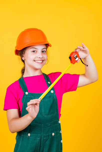 length. construction worker with tape measure. Cute kid as a construction worker. kid repairing home. happy childhood. self-retracting metal tape measure. Little girl using a measuring tape - Foto, Imagen