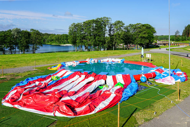 grandes atrações infláveis coloridas achatadas sem ar em uma bela manhã de verão junto ao lago - Foto, Imagem