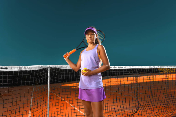 Joueur de tennis. Belle adolescente et athlète avec raquette en vêtements de sport rose et chapeau sur le court de tennis. Concept mode et sport. - Photo, image