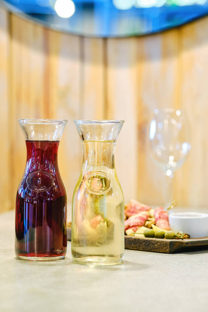 背景にスナック付きのワインとプレートを持つ2つのデカンタ(フィールドの浅い深さのソフトフォーカス写真) - 写真・画像