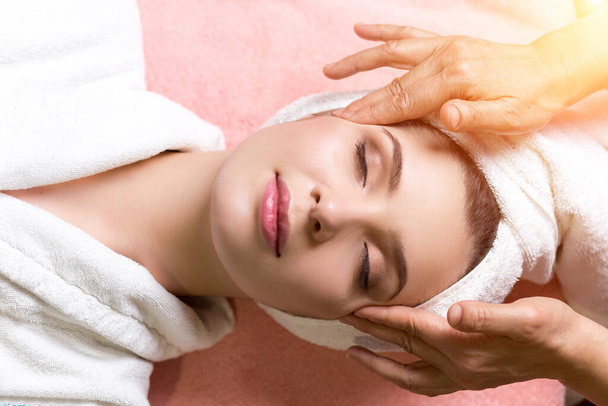 woman lying with closed eyes and having face or head massage in spa - Valokuva, kuva