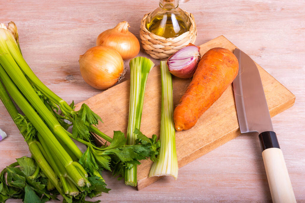 Porkkana ja selleri sipuli vihanneskastike - ainekset Mirepoix ja Soffritto oliiviöljyn kanssa puupöydällä - Valokuva, kuva