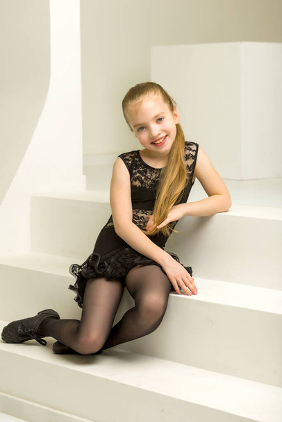 Little girl in a dance costume is sitting on the stairs. - Foto, immagini