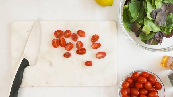 Kesme tahtasındaki vişneli domatesler düzdü. Domates tarifli marul salatası. - Fotoğraf, Görsel
