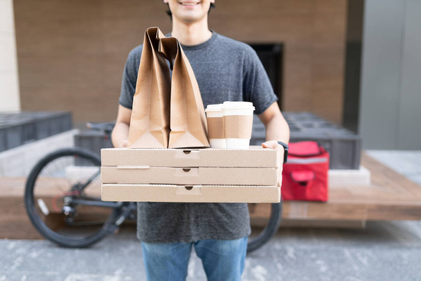 Розрив доставки їжі чоловік несе посилку, стоячи на пішохідній доріжці
 - Фото, зображення