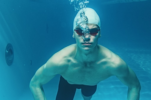 Человек в плавательной шапке и гуглы под водой в бассейне
 - Фото, изображение