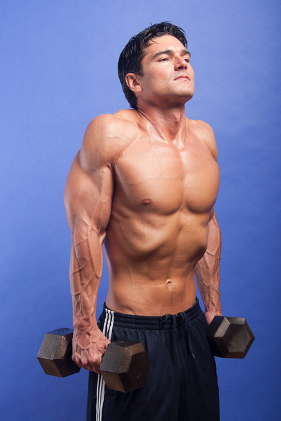 Der heiße Kerl trainiert seine Muskeln. - Foto, Bild