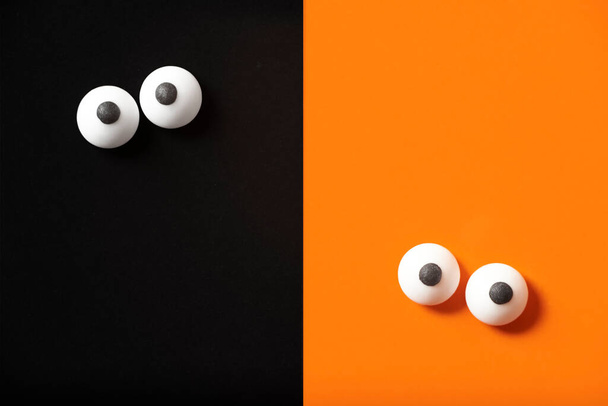 Design d'Halloween drôle, deux paires d'yeux penchés, fond orange et noir, espace de copie. - Photo, image