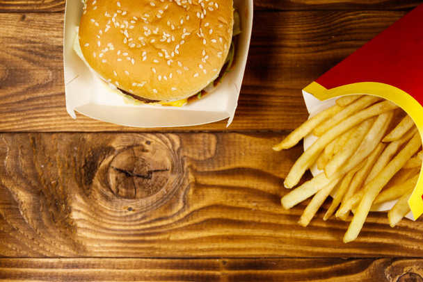 Big hamburger and french fries on wooden table. Top view, copy space - Photo, Image