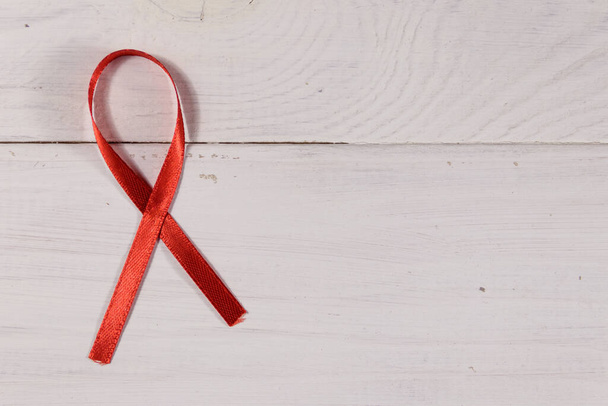 Червону стрічку СНІДу на білому дерев'яному тлі. Копіювальний простір - Фото, зображення