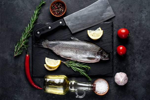 Taş zeminde baharat ve malzemelerle çiğ balık alabalığı. - Fotoğraf, Görsel