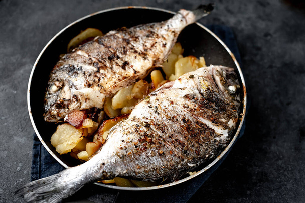 sült dorádó hal és burgonya egy kő háttér - Fotó, kép