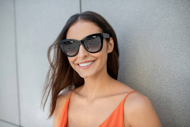 Dark-haired pretty woman in sunglasses smiling nicely - Photo, image