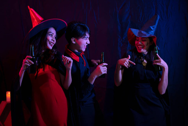 Jonge Thaise mensen in kostuums vieren Halloween. Groep van jonge gelukkige vrienden dragen Halloween kostuums hebben plezier op het feest in de nachtclub door het doen van griezelige gezichten. - Foto, afbeelding