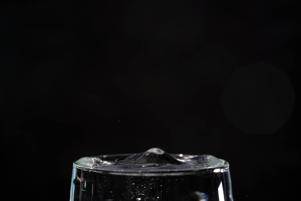 Un primer plano de gotas de agua en el vidrio sobre un fondo oscuro - Foto, imagen