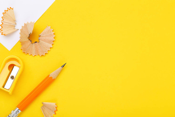 Short pencil with shavings and sharpener on yellow background - Φωτογραφία, εικόνα