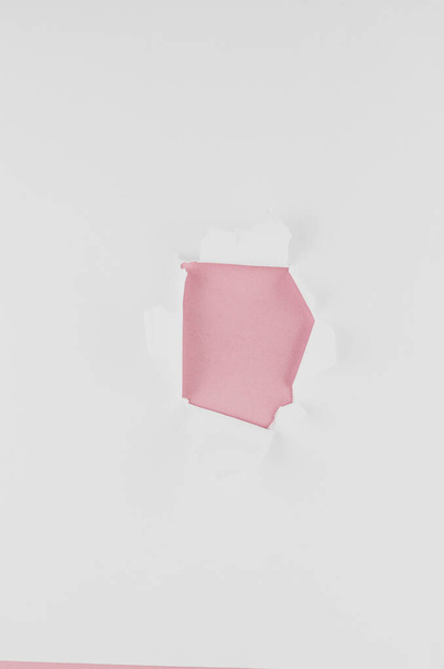 A closeup shot of a pink hole on a white paper with a copy space - Fotó, kép
