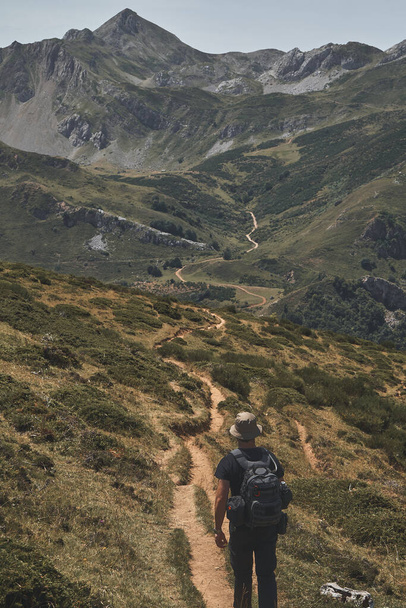 A vertical shot of a hiker on a long hiking trail through the mountains at Somiedo natural park in Spain - Foto, Imagen