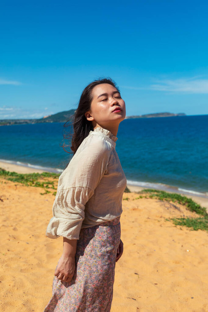 A vertical shot of a young Asian lady on the beach - Zdjęcie, obraz