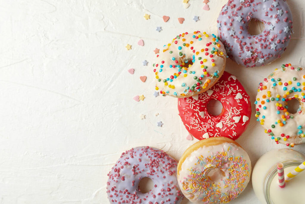 Milk and tasty donuts on white background, top view - 写真・画像