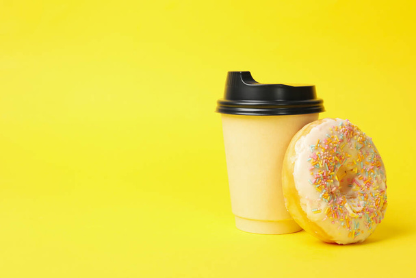 Χάρτινο κύπελλο και ντόνατ σε κίτρινο φόντο - Φωτογραφία, εικόνα