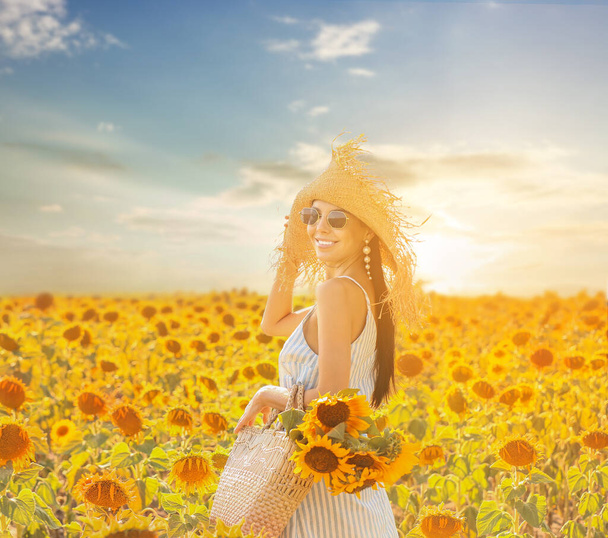 晴れた日のひまわり畑の美しい若い女性 - 写真・画像