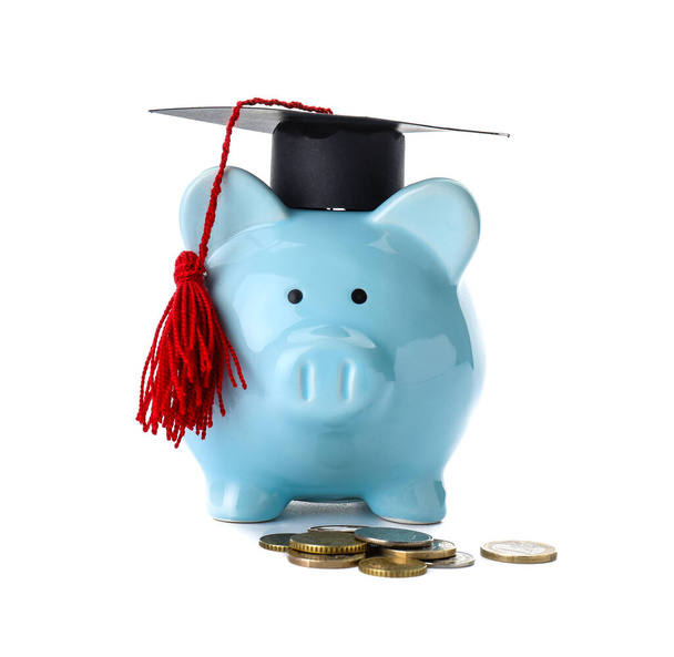 Sombrero de graduación, alcancía y dinero sobre fondo blanco. Concepto de tasas - Foto, imagen