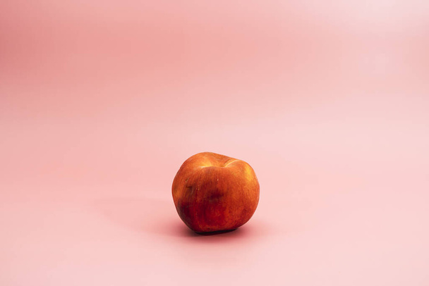A peach isolated on smooth pink background - Фото, зображення
