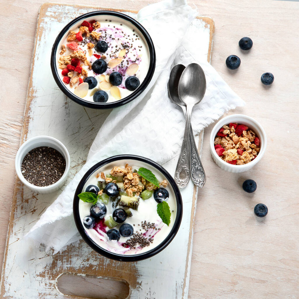 Yogurt breakfast bowls with granola and fruits. Concept of healthy breakfast. Top view, flat lay, copy space. - Φωτογραφία, εικόνα