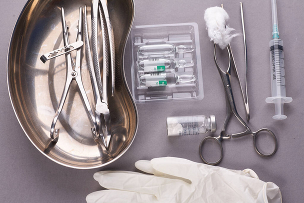 Tandheelkundige apparatuur in steriele verpakking op grijze achtergrond. Medische handschoenen. - Foto, afbeelding