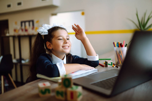 Online remote learning.  Distance education. The girl raises her hand to answer the teacher's question. Covid-2019. - Фото, зображення