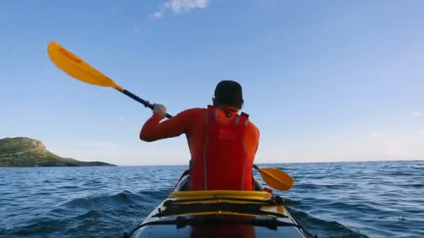 Widok z tyłu człowieka wiosłujący kajak morski - Materiał filmowy, wideo