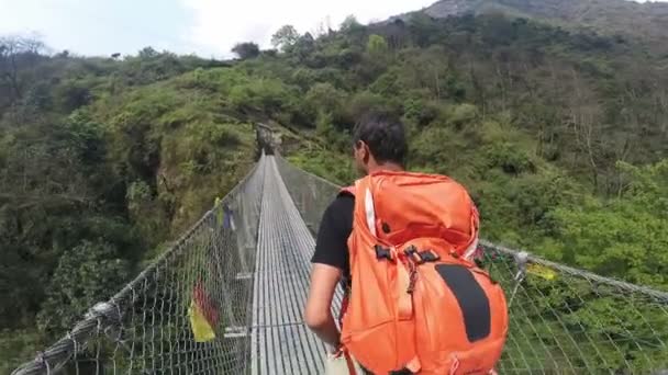 Guia cruzando ponte suspensa em trekking na região do Himalaia de Annapurna - Filmagem, Vídeo