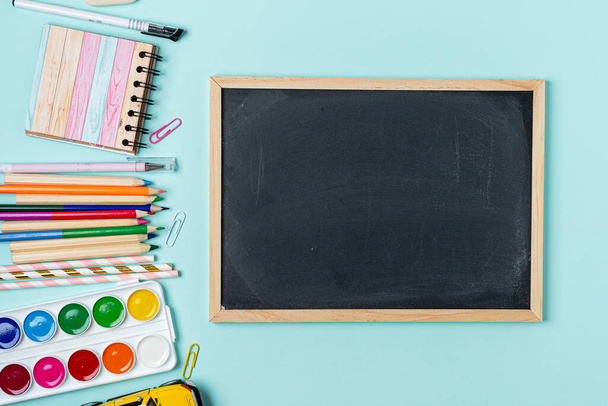 Konzept Back To School Color Chalk Bleistift Notizbuch Schreibwaren auf blauem Blackboard Hintergrund. Design Copy Space und Attrappen Zubehör Top View Flat Lay - Foto, Bild