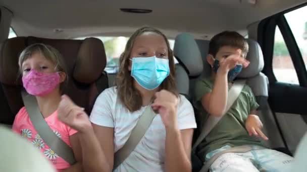 Bělošský teenager a dvě děti na zadních sedadlech auta s ochrannými maskami. Oni tancují. Koncepce nových pravidel, nová normalita, pandemie koronaviru. - Záběry, video