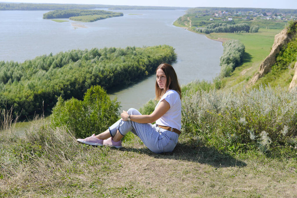 beautiful middle age woman sitting over high river bank. tranquil place for relaxation and calm. mind balance and inner peace concept. woman and beautiful landscape. real people. - Photo, Image
