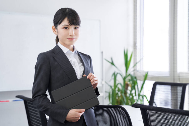 Una mujer de negocios japonesa con una tableta en su oficina - Foto, imagen