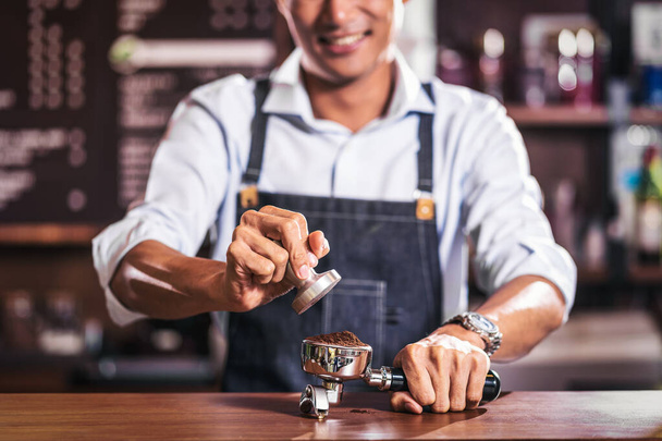 Asian Barista tamping the portafilter and preparing cup of coffee, espresso with latte or cappuccino for customer order in coffee shop, Small business owner and startup in coffee shop concep - Φωτογραφία, εικόνα