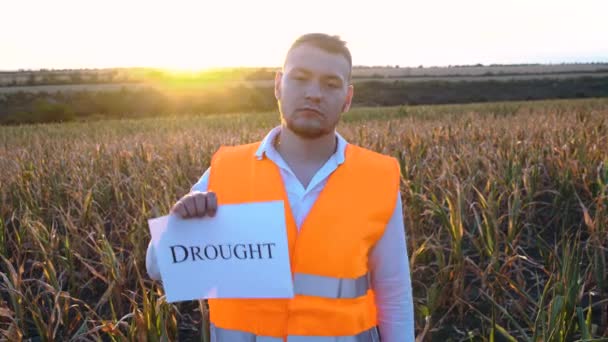 Портрет грустного молодого фермера с табличкой с надписью "Засуха" . - Кадры, видео