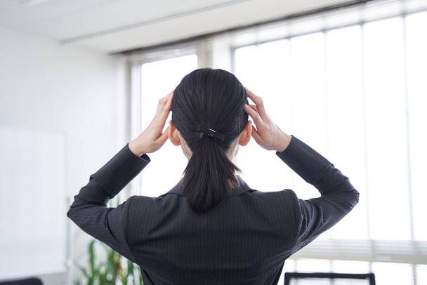Задня частина японської жінки в офісі з головою в руках. - Фото, зображення