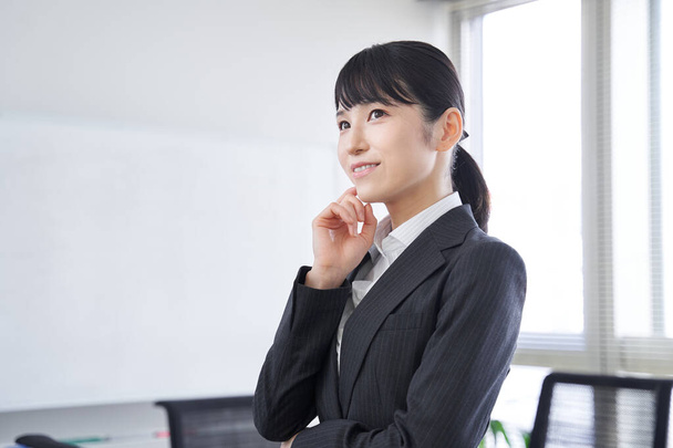 Una mujer japonesa en su oficina pensando - Foto, imagen
