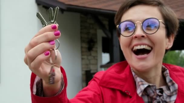 Όμορφη γυναίκα με γυαλιά κρατά τα κλειδιά από το νέο σπίτι. Επιχειρηματίας κυρία είναι ευτυχής να αγοράσει ένα διαμέρισμα. - Πλάνα, βίντεο