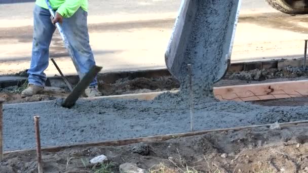 Constructores de mano de obra en obra llenando encofrados con trabajadores de cemento en el proceso formando nueva acera de hormigón - Metraje, vídeo